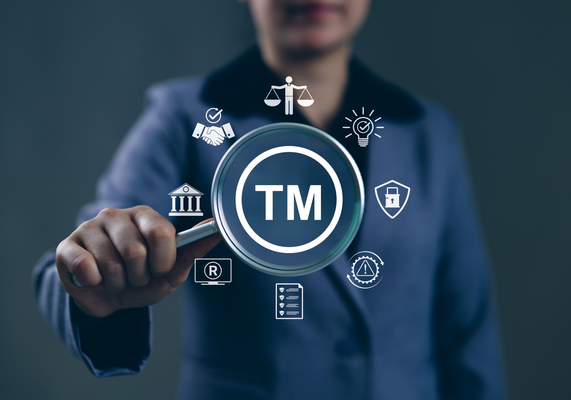 TM, Trademark Protection, Intellectual Property Concept. Person holding magnifying glass with "TM" symbol, icons of intellectual property, legal, patents, security, copyright, registered trademark,